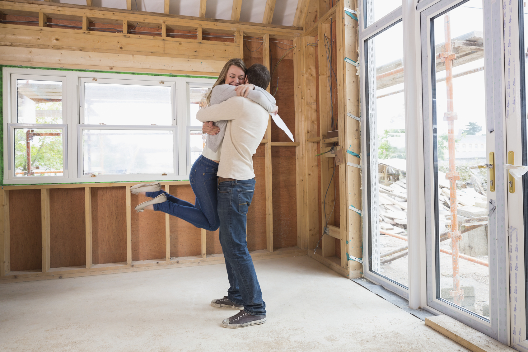 Man hugging wife in house site