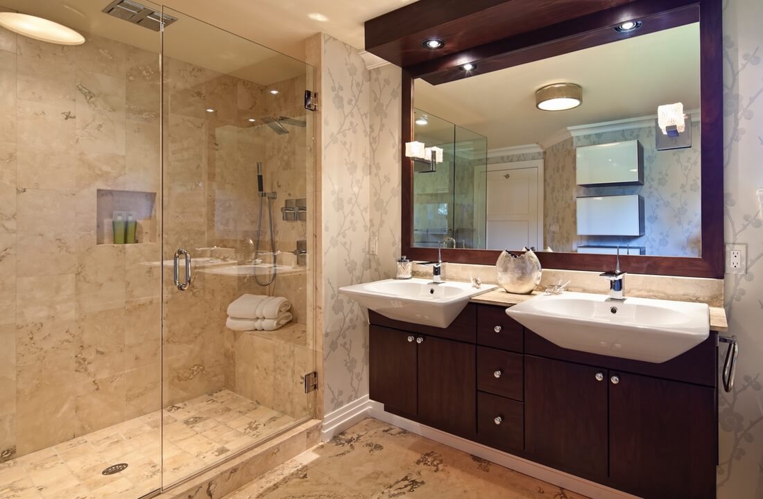 Luxurious bathroom remodeled with natural stone shower and cherry wood vanity